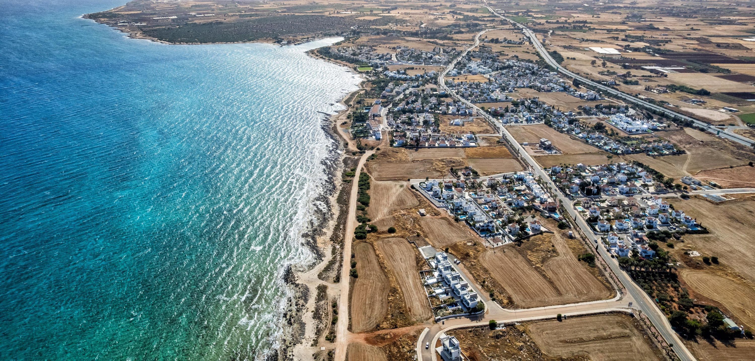 An aerial view of a coastal town with residential areas, roads, and a beach.