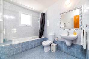 A bathroom with a bathtub, toilet, sink, and a large mirror.