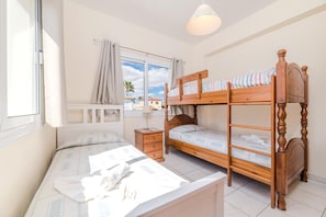Ein Schlafzimmer mit Etagenbett, Nachttisch, Lampe und einem Fenster mit Vorhängen.