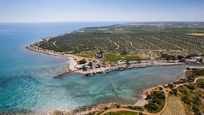 An aerial view of a coastal area with a marina, boats, and a small island with buildings.