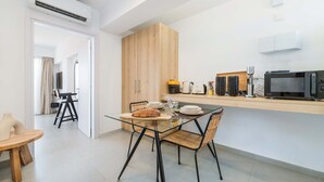 A modern kitchen with a glass dining table, wicker chairs, and wooden cabinets. - Finikoudes Marina View 202 (Larnaca)