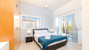A bedroom with a bed, bedside tables, a window, and a balcony. - Nemea Serenity Blue in Ayia Napa (Ayia Napa)