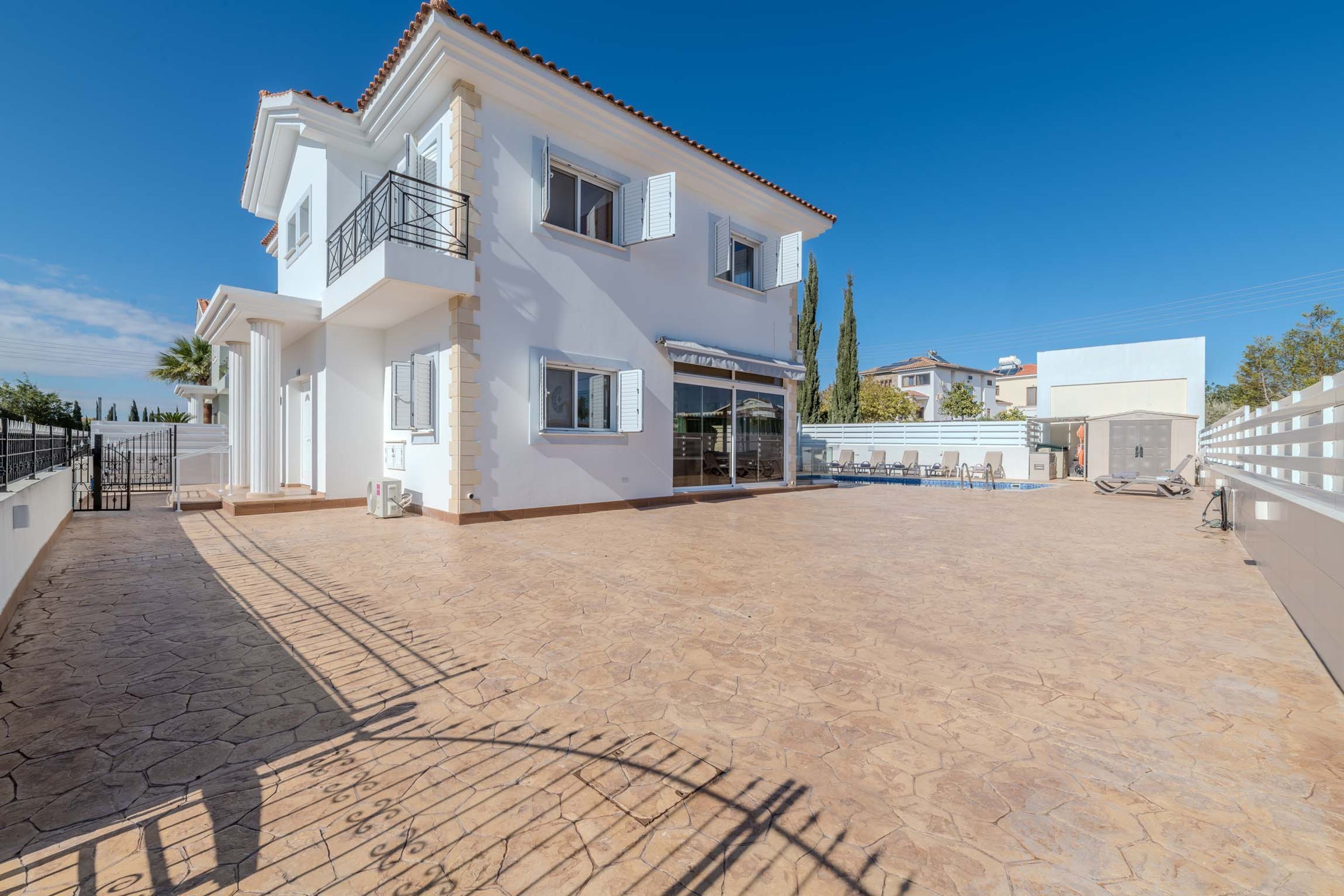 Una casa de dos pisos con un patio empinado, un espacio al aire libre cubierto y una piscina.