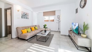Una sala de estar moderna con sofá, mesa de centro, televisor y plantas.