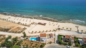 An aerial view of a coastal property with a swimming pool, beach access, and a small building. - Villa Stephanie Oasis (Sotira)