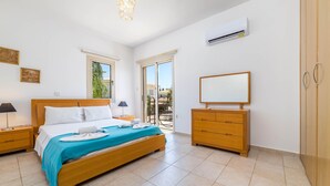 Ein Schlafzimmer mit Bett, Nachttischen, einem Schminktisch und einer Klimaanlage.