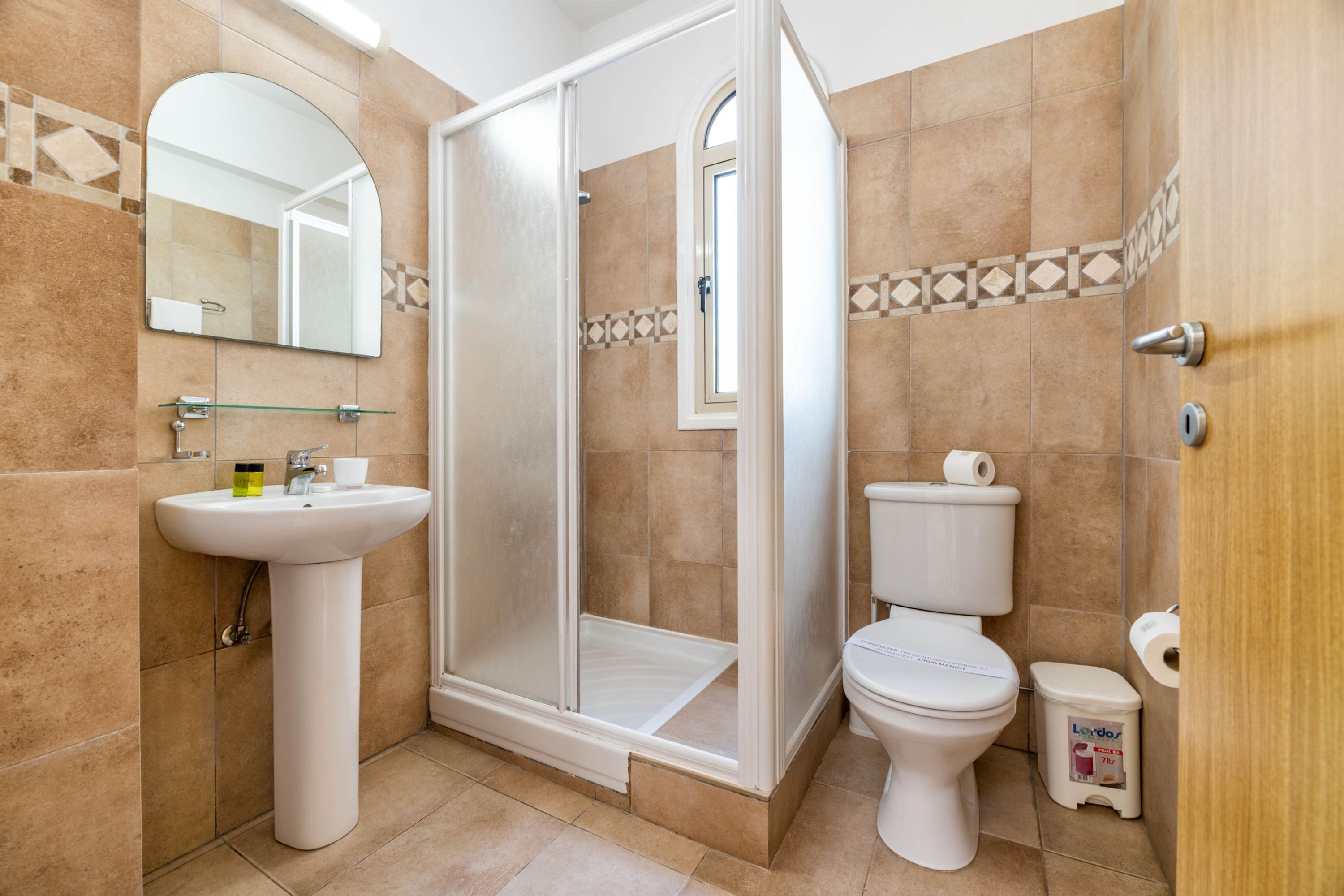 Een badkamer met douche, toilet, wastafel en spiegel.