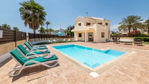 A swimming pool with lounge chairs, a building with balconies, and palm trees. - Villa Sarah in Ayia Napa (Sotira)