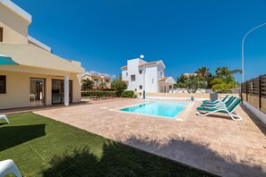 A modern residential area with a swimming pool, green lawn, and a row of sun loungers. - Villa Sarah in Ayia Napa (Sotira)