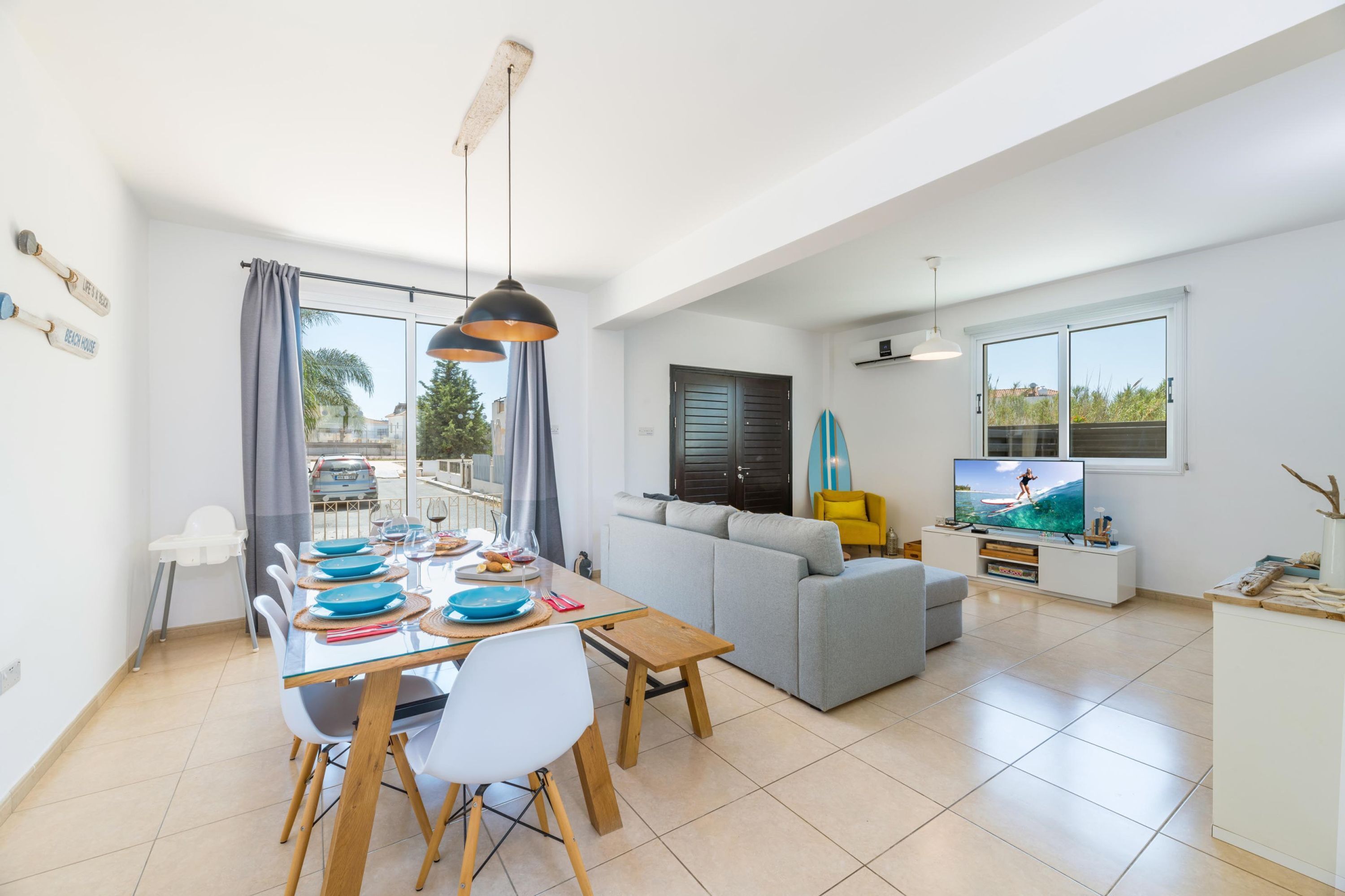 A modern living room with a dining area, a sofa, and a TV.