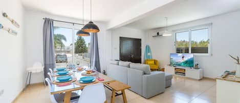 A modern living room with a dining area, a sofa, and a TV.