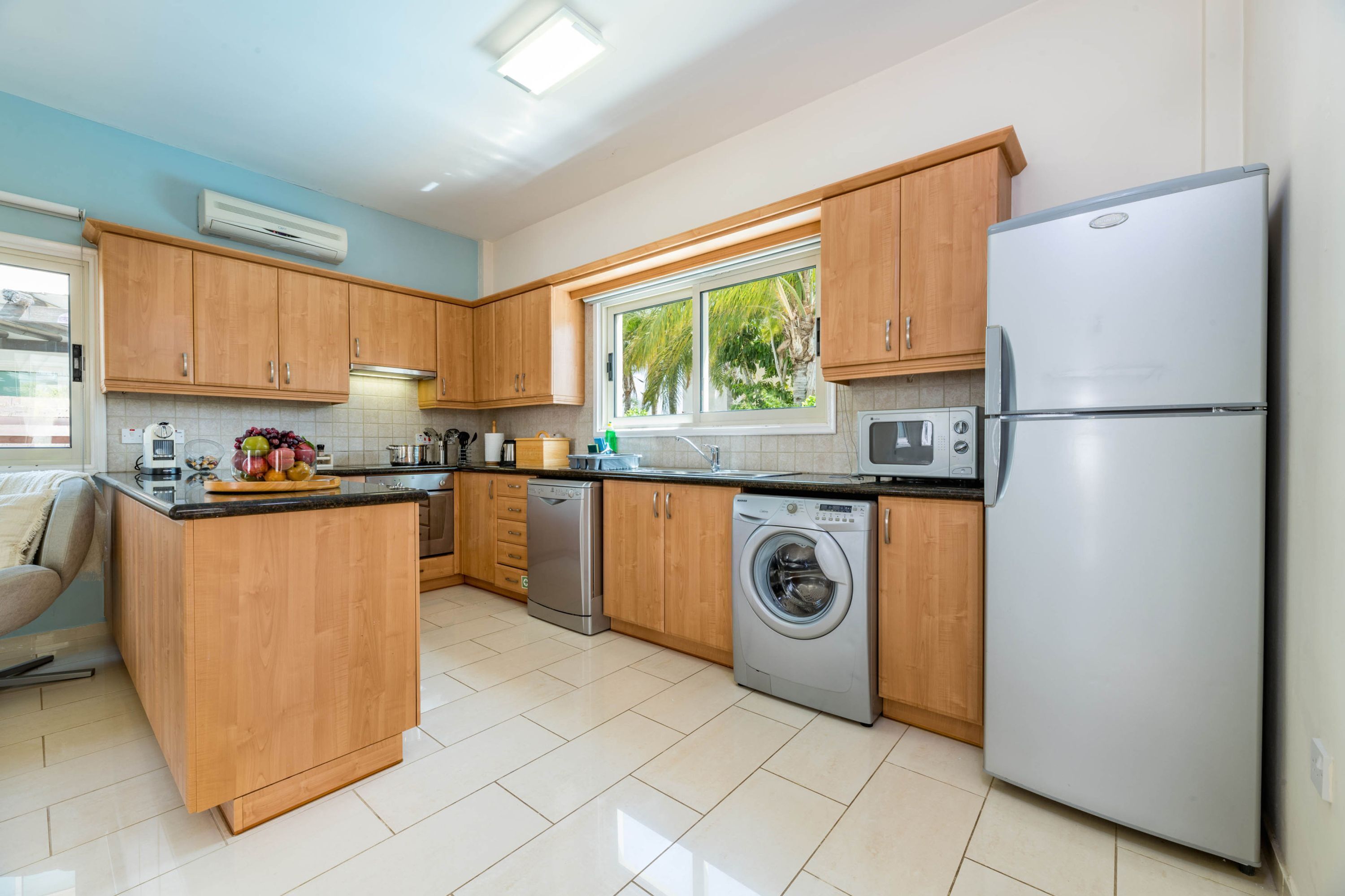 A modern kitchen with wooden cabinets, stainless steel appliances, and a window providing natural light.