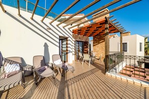 A sunlit outdoor patio with lounge chairs, a table, and a pergola. - Villa Anna Maria in Ayia Napa (Sotira)