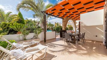 A patio with sun loungers, a dining table, and chairs.