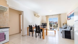 Un appartement moderne comprenant une cuisine, un coin repas et un salon. Il est équipé d’une table à manger avec des chaises, d’un canapé et d’un téléviseur.