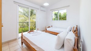 Een slaapkamer met twee bedden, een balkon en een raam.