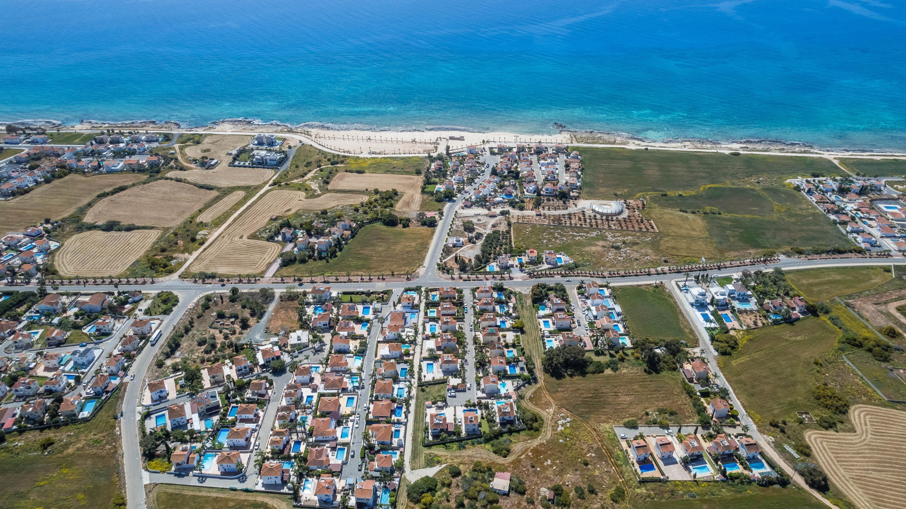 Vista aérea de uma área residencial costeira, com casas, ruas e uma praia.