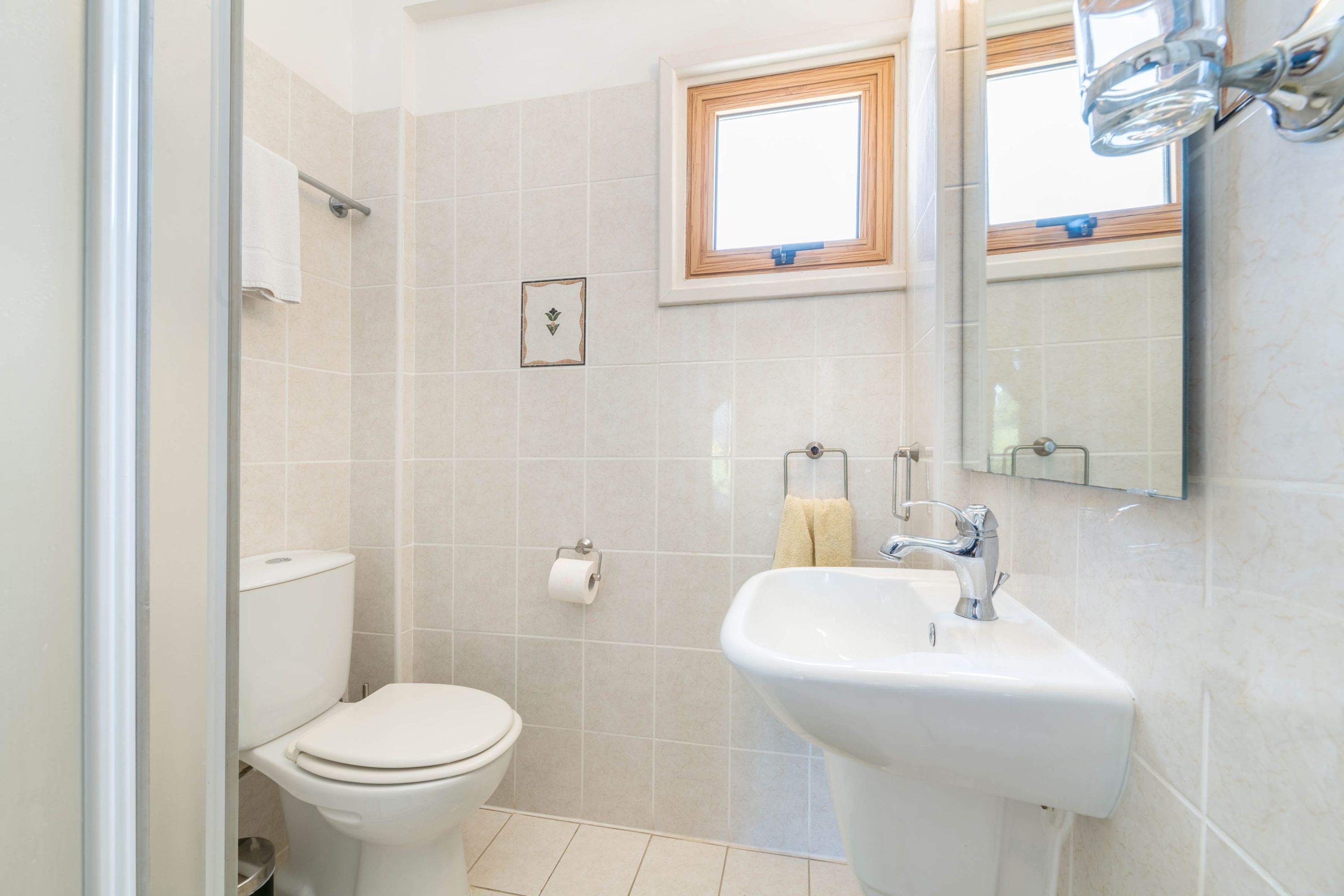 A bathroom with a toilet, sink, and a window above the sink.