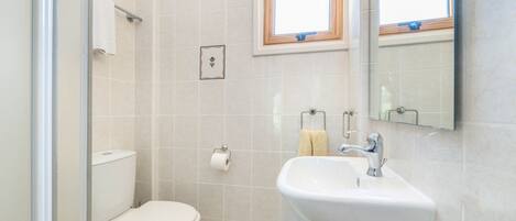 A bathroom with a toilet, sink, and a window above the sink.