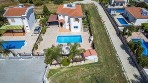 A residential area with multiple houses, a swimming pool, and a paved walkway. - Elena Gardens Villa in Ayia Napa (Sotira)
