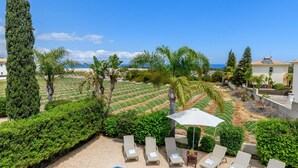 A swimming pool with lounge chairs and a view of the sea. - Villa Alexander in Protaras (Paralimni)