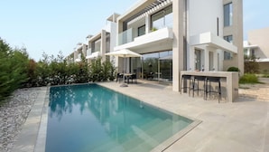 A modern residential building with a swimming pool, outdoor seating, and a pergola. - Azure Seaview - Amber Villa (Paralimni)