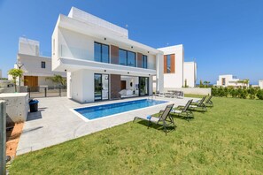 Une maison moderne à deux étages, dotée d’une piscine, d’un patio couvert et d’une pelouse bien entretenue.