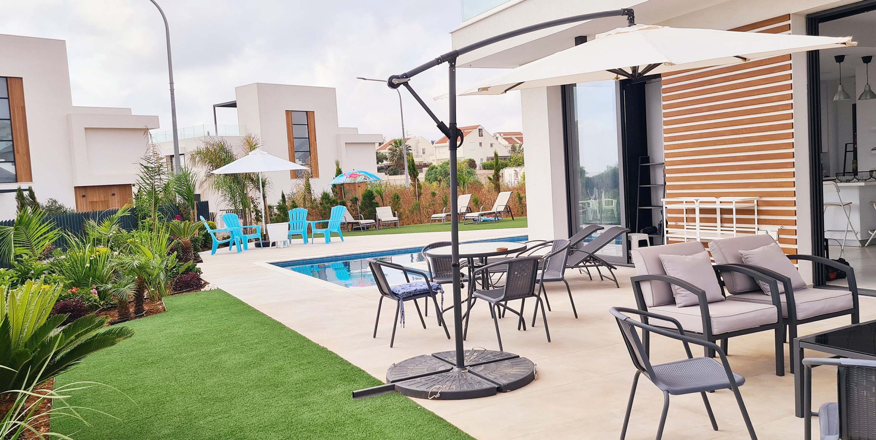 Une terrasse extérieure moderne avec une piscine, des chaises longues et des parasols.