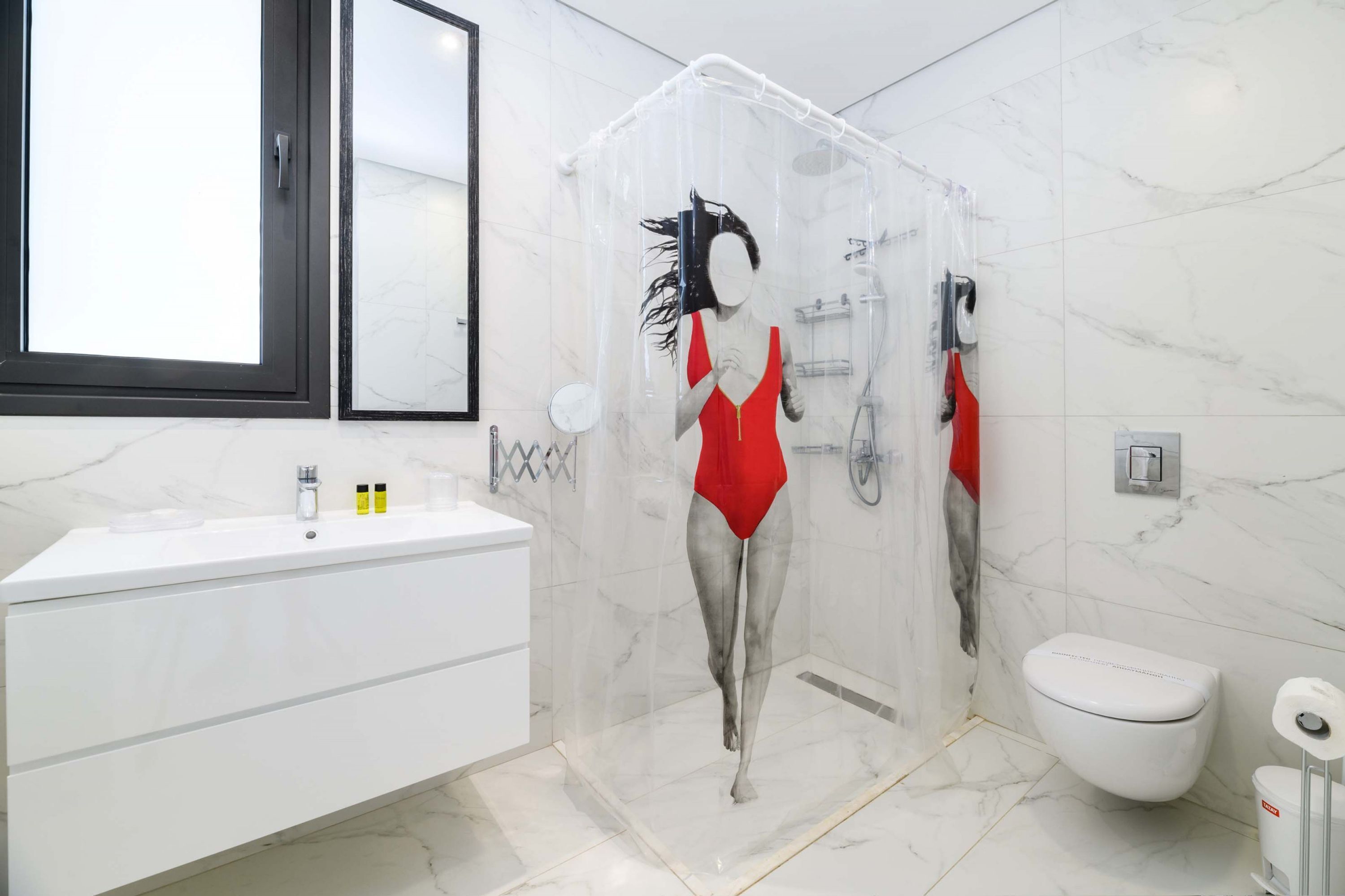 Een moderne badkamer met een grote spiegel, een witte wastafel, een toilet en een douchecabine.