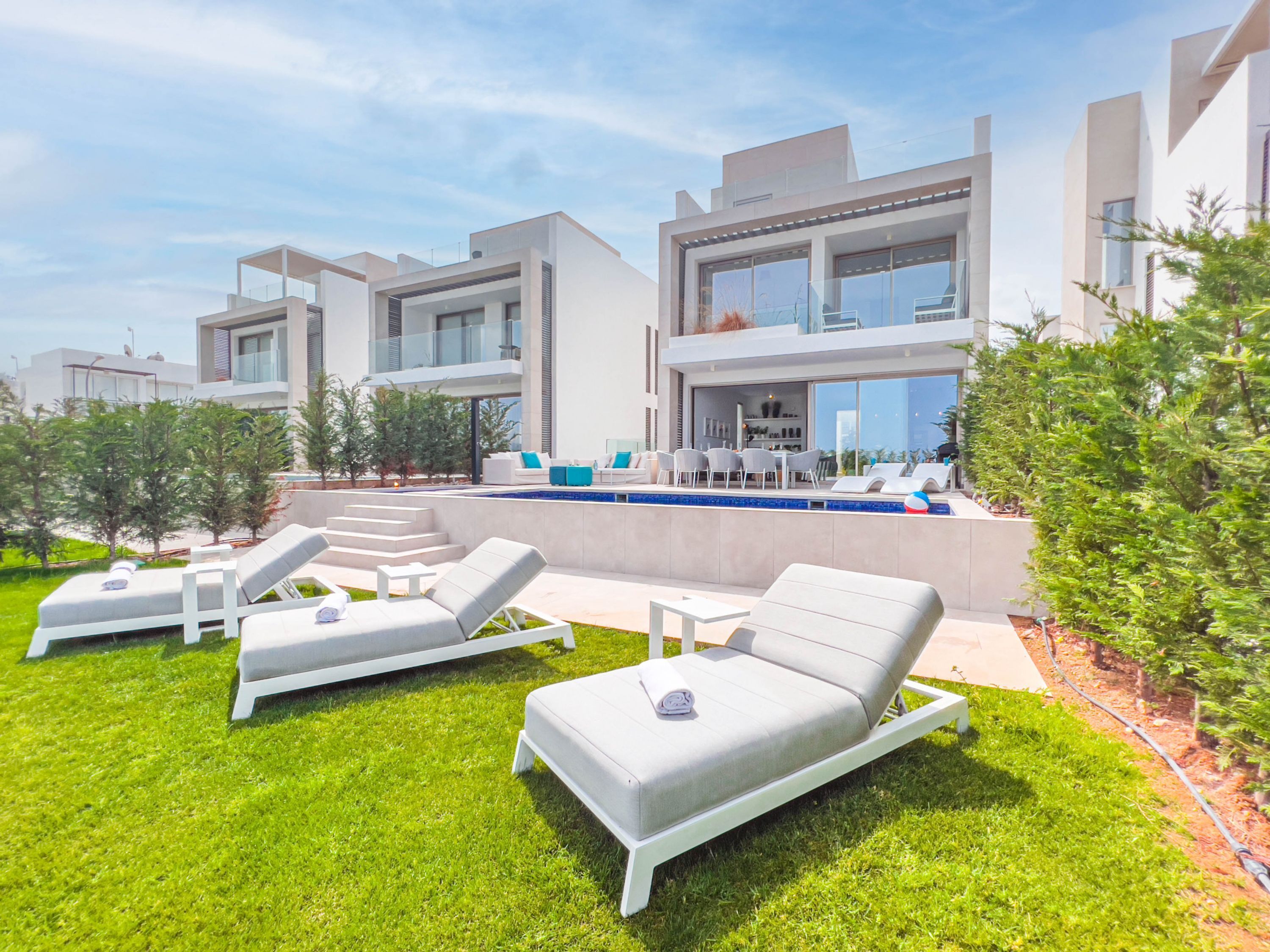 Une maison moderne dotée d’une piscine, d’un espace salon extérieur et d’une pelouse bien entretenue.