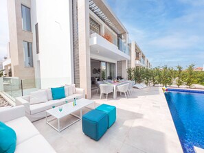 A modern outdoor living area with a pool, white furniture, and a dining table set up for an outdoor meal. - Azure Seaview - Jade Villa (Paralimni)