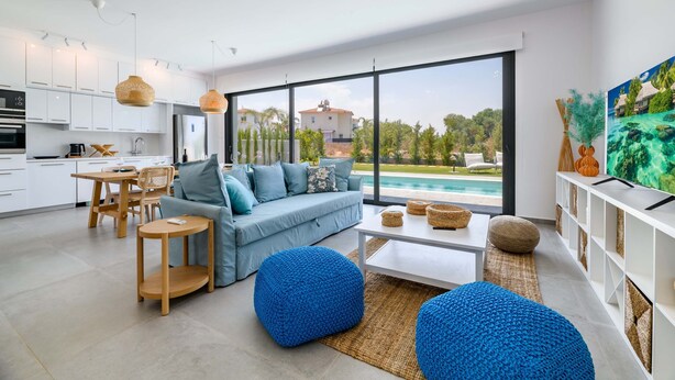 Una sala moderna con un sofá, otomanas y una zona de comedor.