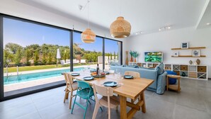 Una sala moderna con comedor, ventanas amplias y vista a la piscina.