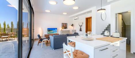 A modern kitchen with a central island, white cabinetry, and pendant lighting.