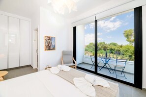 Une chambre d’hôtel moderne dotée d’un grand lit, d’un coin salon avec vue et d’un balcon aménagé avec du mobilier d’extérieur.