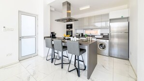Una cocina moderna con una isla central, electrodomésticos integrados y una lavadora.