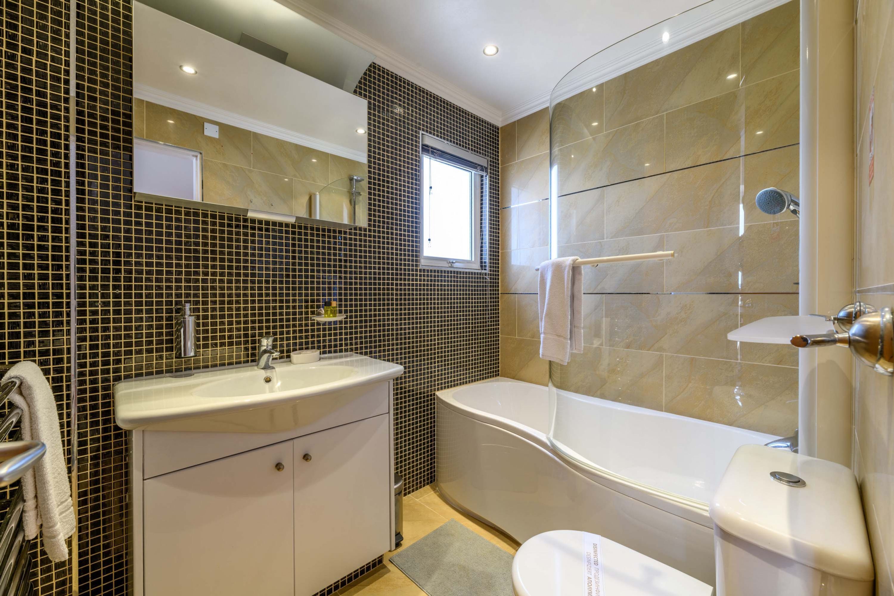A modern bathroom with a large sink, mirror, and bathtub.