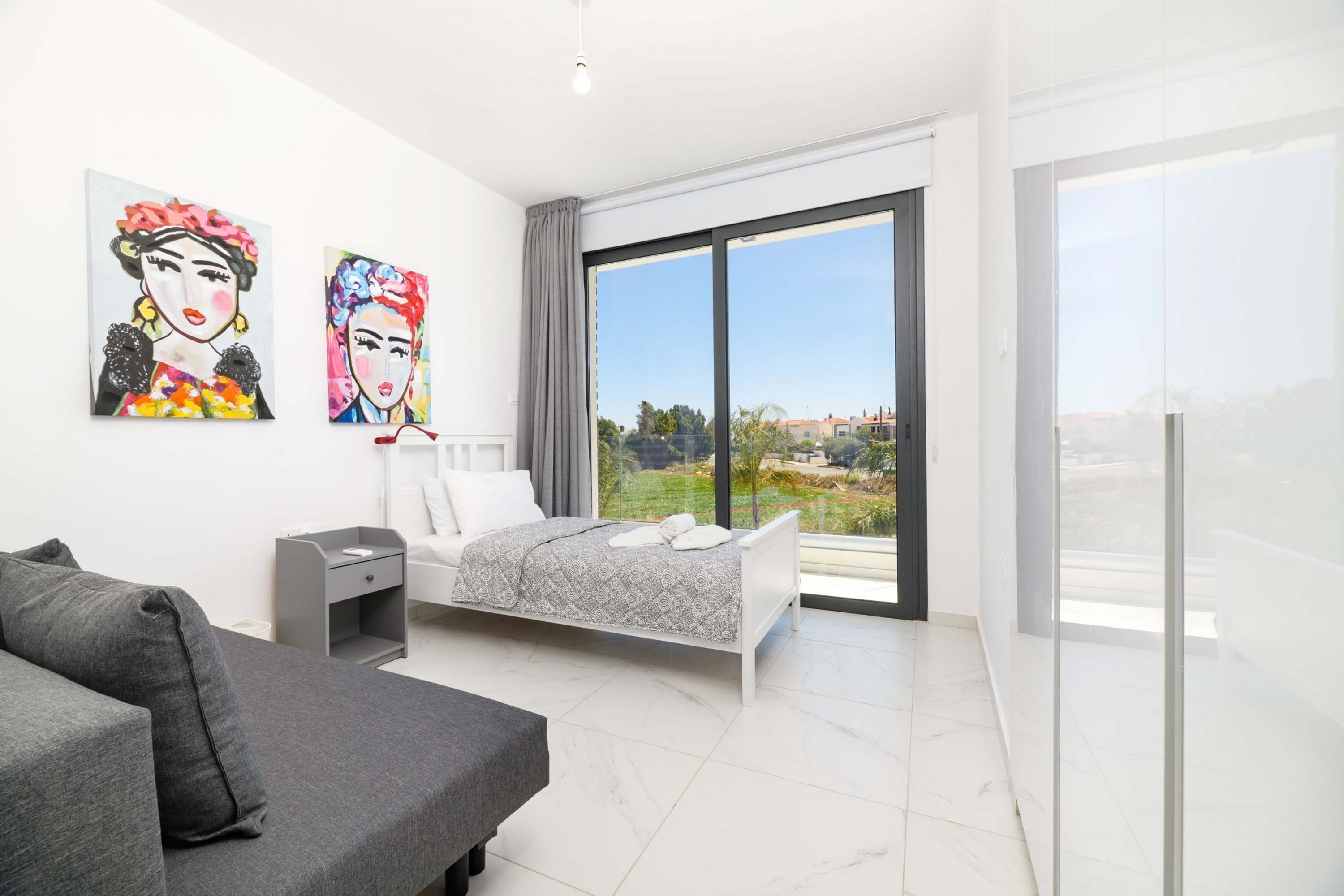 Une chambre à coucher moderne avec un lit, un canapé et deux tableaux accrochés au mur.