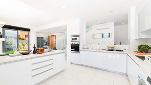 Una cocina moderna con armarios blancos, horno empotrado, microondas y lavadora.