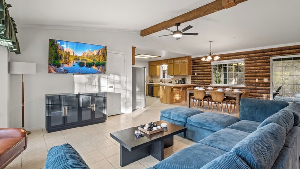 Una sala de estar moderna con un sofá azul grande, una mesa de centro y un televisor montado en la pared.