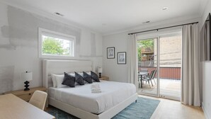 Un dormitorio moderno con una cama grande, un escritorio y vistas a un balcón exterior.