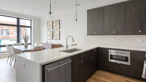 Una cocina moderna con armarios de madera oscura, encimera blanca y electrodomésticos de acero inoxidable.