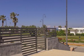 A gated entrance with a metal fence, a street lamp, and a building in the background.