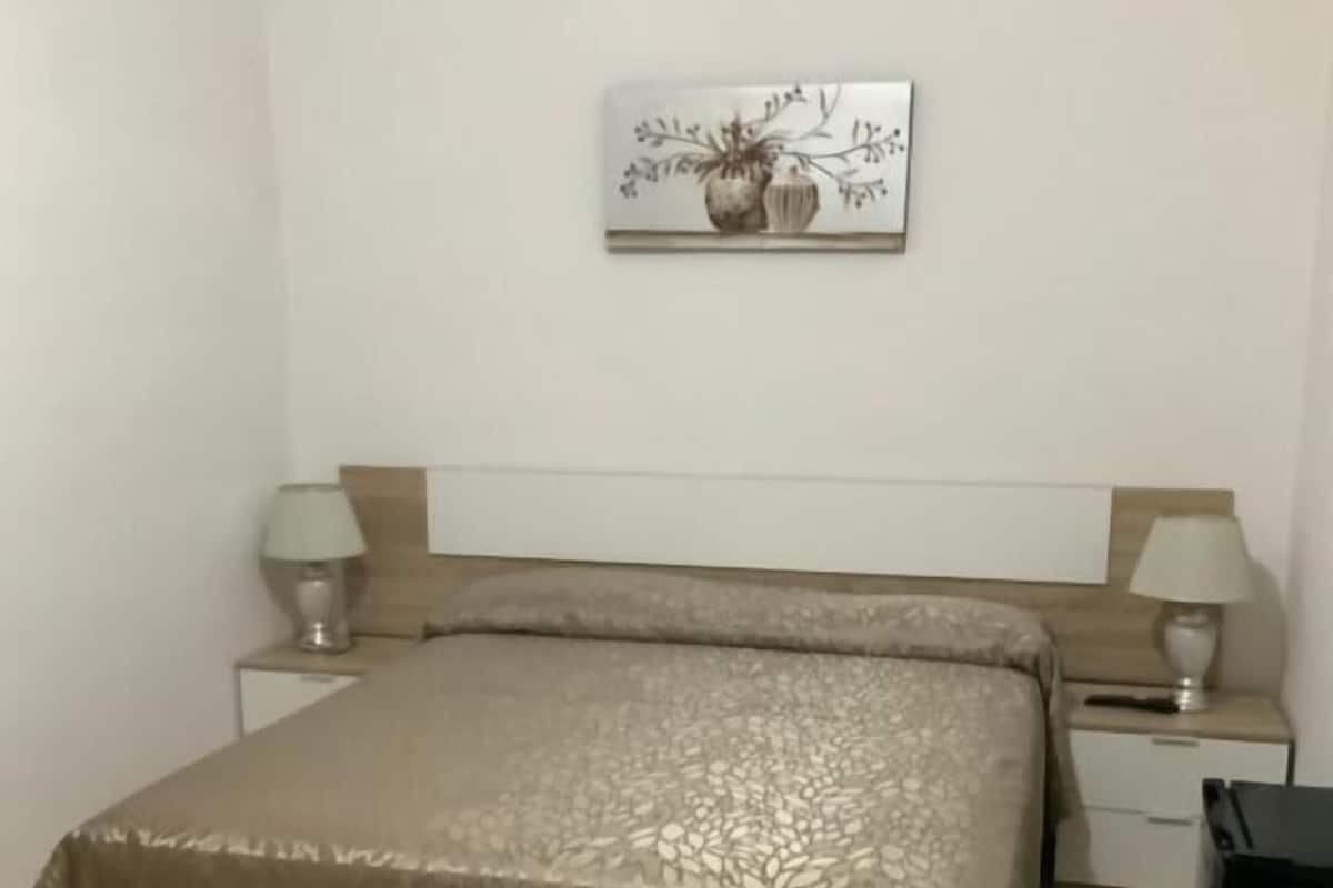 Un dormitorio con una cama, dos mesitas de noche y una obra de arte colgada en la pared.