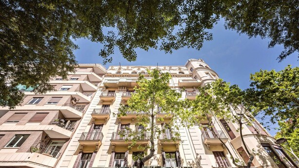 Un edificio a più piani con balconi, ampie finestre e un cielo sereno.