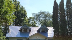 A two-story house with a gabled roof, a front porch, and a small front yard. - 2-bedroom Lakeview house near Tupper Lake with AC, WiFi, Deck, Gazebo, Firepit (Piercefield)
