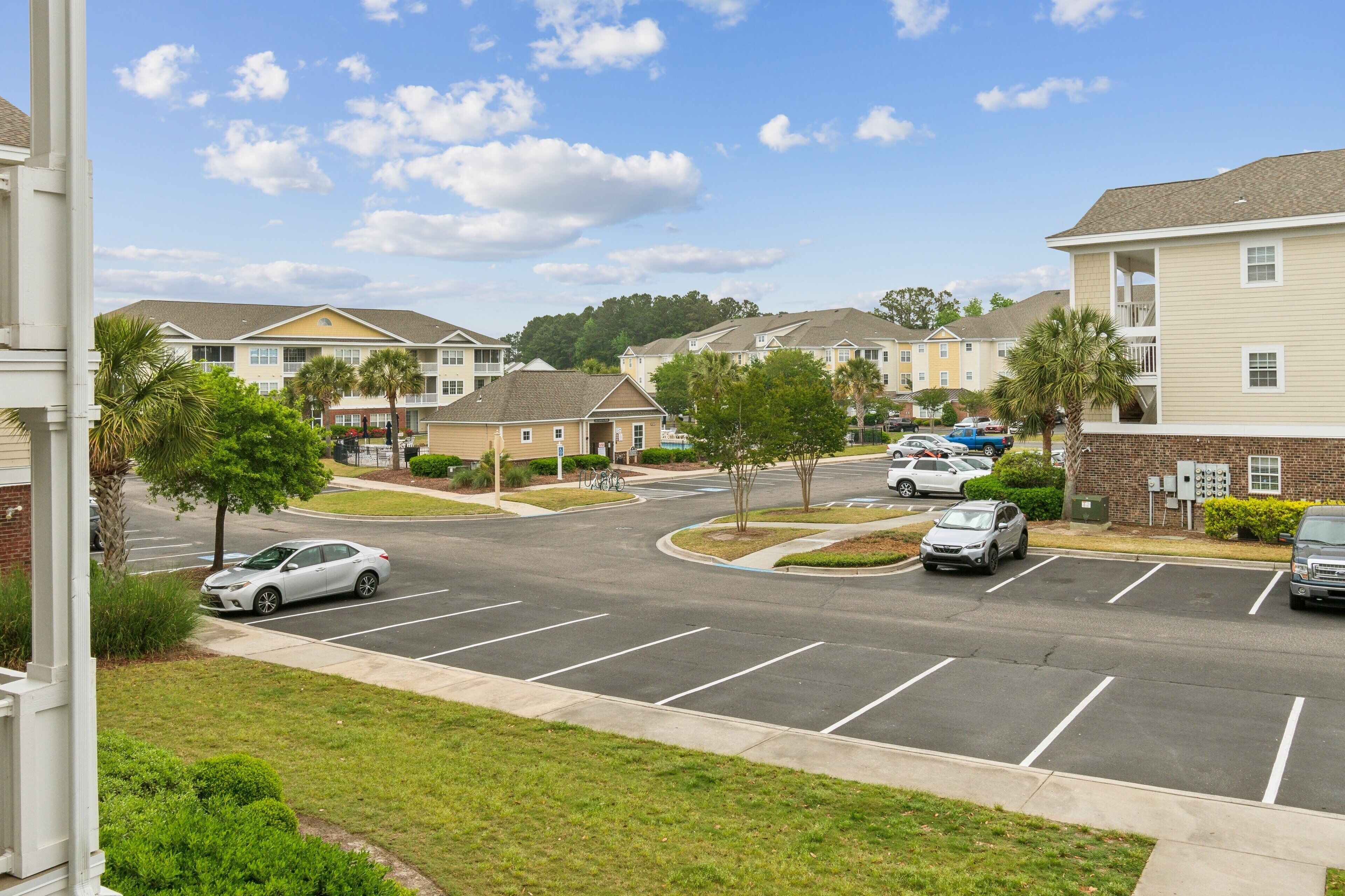 A residential area with a parking lot, houses, and a clear sky.
