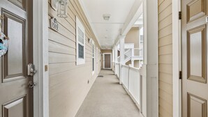 A corridor with wooden doors, white railings, and a beige carpet. - Havens On The Nine 2 Bedroom Condo (North Myrtle Beach)