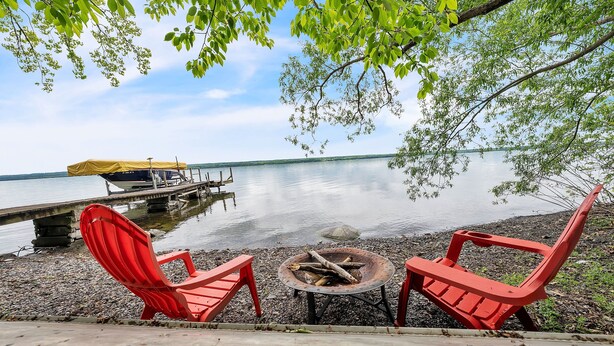 A lakeside setting with two red Adirondack chairs and a small fire pit. - Peaceful Lakefront Getaway On Cayuga Lake 4 Bedroom Cottage (Aurora)