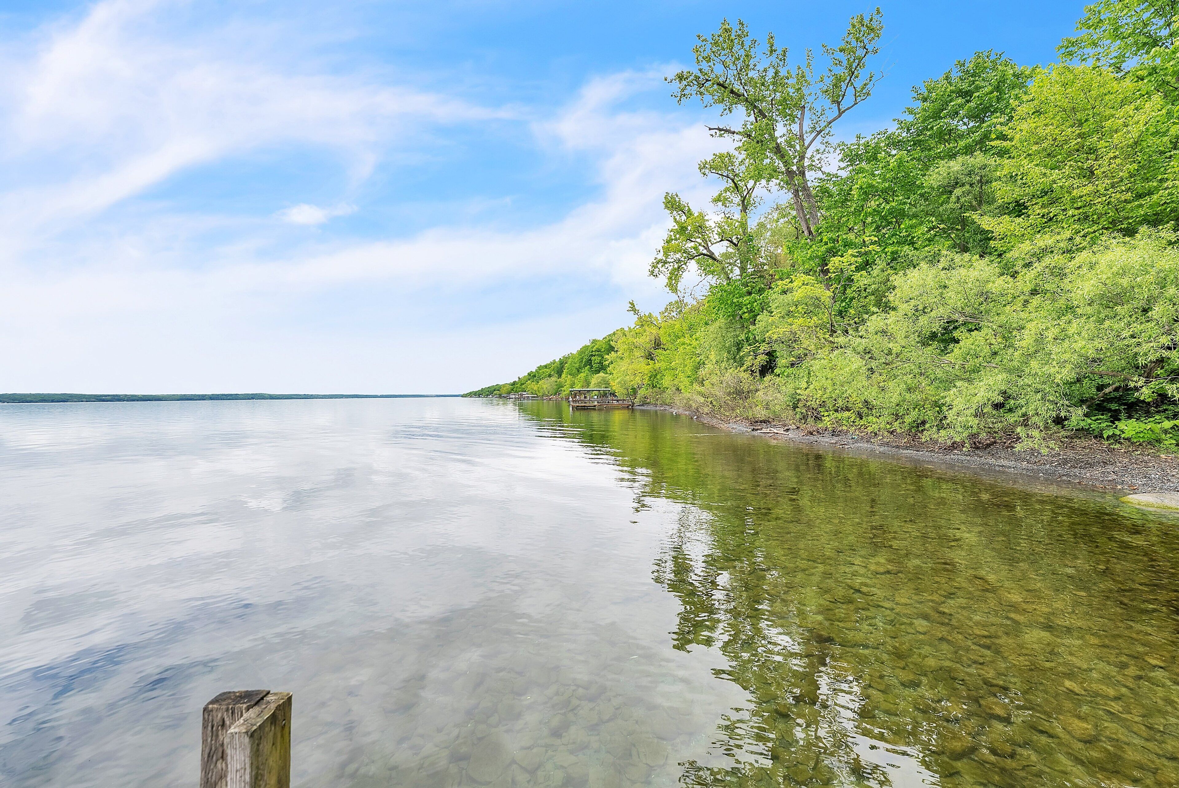 A calm river with clear water reflecting the sky and surrounding greenery.